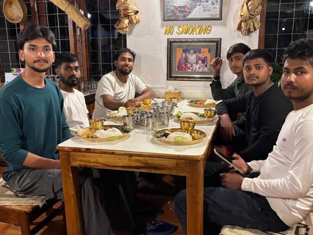 Trekkers sharing dinner around a wooden table in the dining room